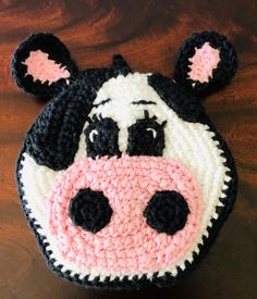 a crocheted cow head sitting on top of a wooden table next to a black and white bag