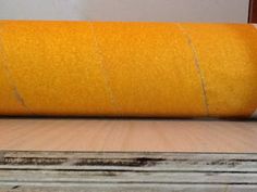 a roll of yellow felt sitting on top of a wooden floor next to a window