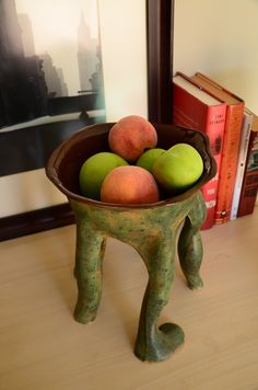 a bowl filled with fruit sitting on top of a wooden table next to a book