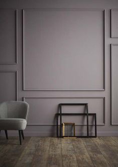 an empty room with two chairs and a table on the floor in front of a gray wall