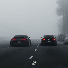 two cars driving on a foggy road in the middle of the day with red tail lights