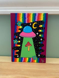 a colorful painting on a shelf with a mushroom and stars in the sky above it