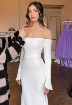 a woman in a white dress standing next to a mannequin