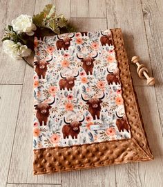 a blanket with an animal print on it and flowers in the background, sitting on a wooden floor