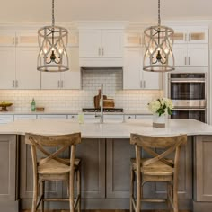 a large kitchen with an island in the middle and two stools at the center