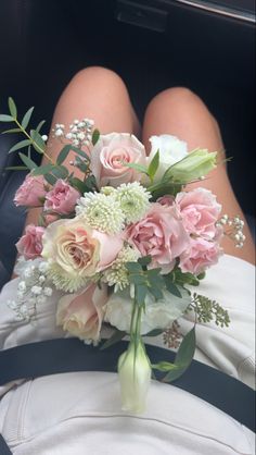 a bouquet of pink and white flowers is sitting on the back of a car seat