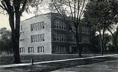 an old black and white photo of a large building with trees in front of it