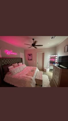 a bed room with a neatly made bed and a neon sign on the wall above it