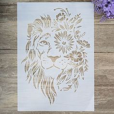 a paper cut with a lion's head surrounded by flowers on a wooden table