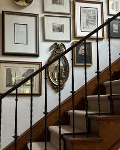 there are many framed pictures on the wall next to the stair case and handrail