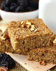 two pieces of oatmeal breakfast bars on a cutting board with berries and milk in the background