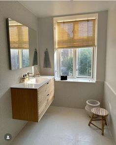 a bathroom with a sink, mirror and stool next to a window in the room