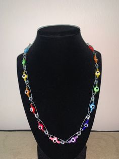 a black mannequin holding a multicolored necklace on it's neck