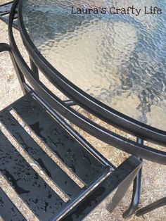 a metal table with a glass top and two chairs sitting on the ground next to it