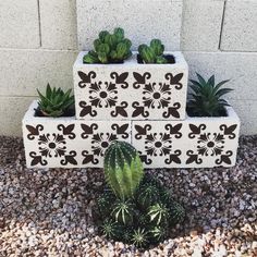 three planters with plants in them are sitting on the ground next to a wall