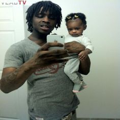 a man holding a baby and taking a selfie in front of a mirror with his cell phone