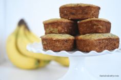 several muffins on a white plate with bananas in the background