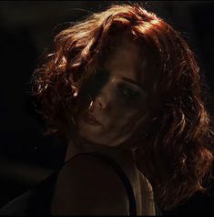 a woman with red hair is staring into the distance