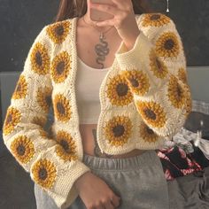 a woman taking a selfie while wearing a sunflower knitted cardigan sweater