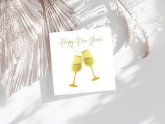 a card with two glasses of wine on it and the words happy new year written in gold