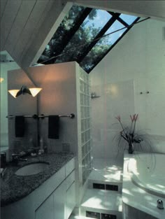 a bathroom with a skylight above the bathtub and sink area, is shown in this image