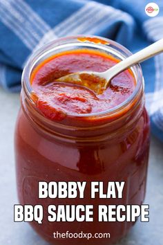 a jar filled with bbq sauce sitting on top of a table next to a blue towel