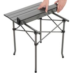 a person holding onto a folding table with their hand on the top and bottom edge