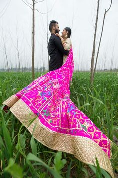 a man and woman standing in tall grass