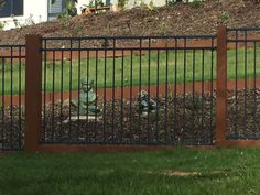 an iron fence is in front of a house with a small statue on the lawn