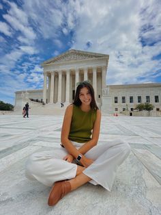 a woman is sitting on the ground in front of the supreme court with her legs crossed