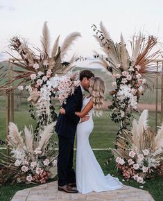 a bride and groom kissing under an archway decorated with pamodia