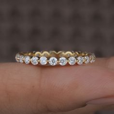 a person's hand holding a yellow gold ring with five round diamonds on it