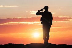 a man standing on top of a hill at sunset