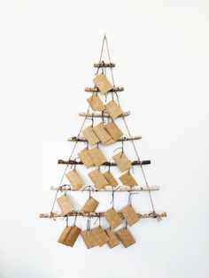 a christmas tree made out of wooden pieces and rope with pictures hanging from it's sides