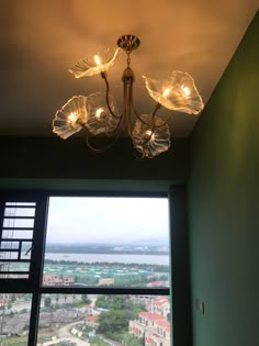 a chandelier hanging from the ceiling in front of a window overlooking a city