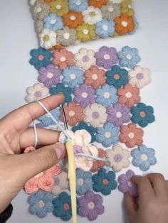 someone is crocheting flowers on the table with yarn and knitting needles in front of them