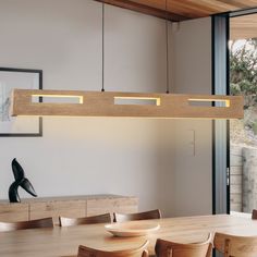 a dining room table and chairs with lights hanging from it's ceiling above them