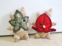 two small crocheted animals are standing next to each other on the floor in front of a wall