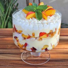 a trifle with fruit and whipped cream in a glass dish on a wooden table