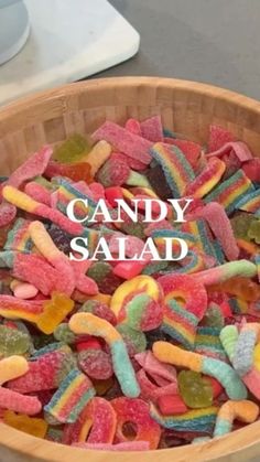 a wooden bowl filled with lots of colorful gummy bears and the words candy salad