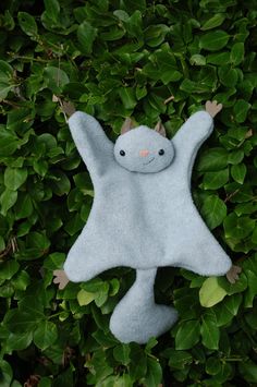 a gray stuffed animal laying on top of green leaves