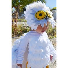 a young child wearing a white and yellow feathered costume with goggles on it's head