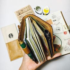 a person holding an open wallet on top of a white table next to other items