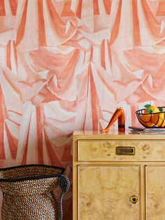 an orange and white striped wallpaper next to a dresser with a basket on it