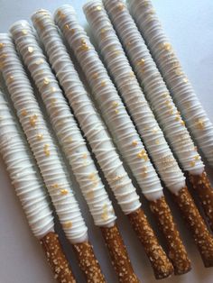 four sticks with white frosting and gold sprinkles are lined up in a row