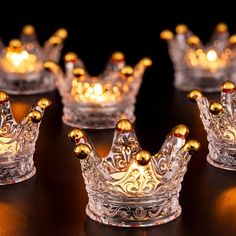 several glass crowns with lights in them on a table