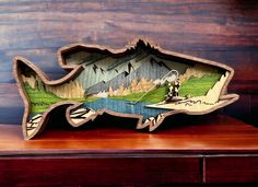 a fish shaped wooden box with a fishing scene on it