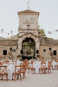 an old building with tables and chairs set up for a formal dinner in front of it