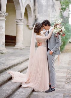 a man and woman standing next to each other in front of an archway with flowers