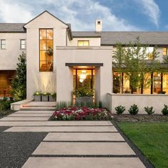 a white house with lots of windows and plants in the front yard at night time